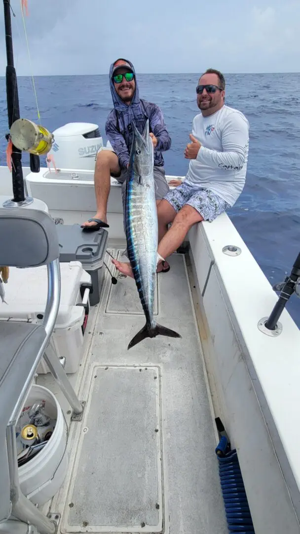 Two anglers proudly holding a large wahoo.