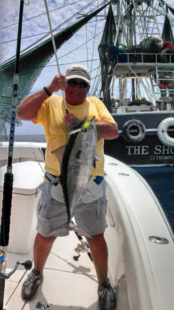 Man holding a large tuna on fishing boat.