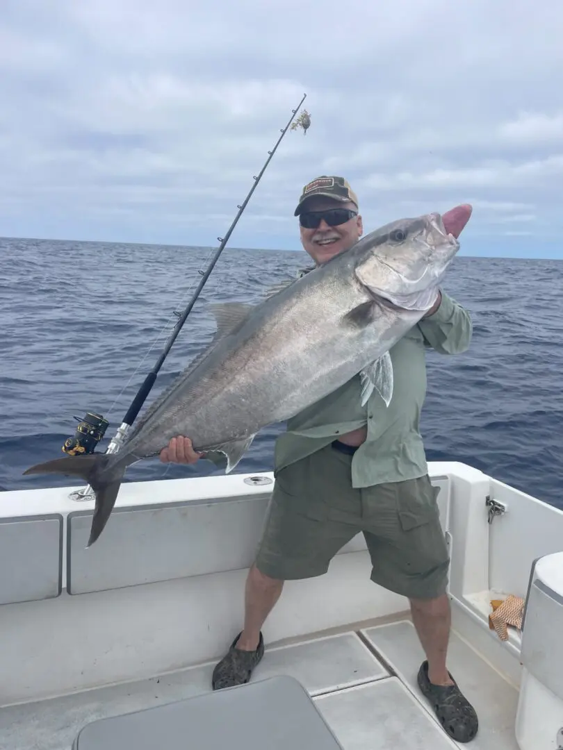 Smiling man holding a large fish on boat.